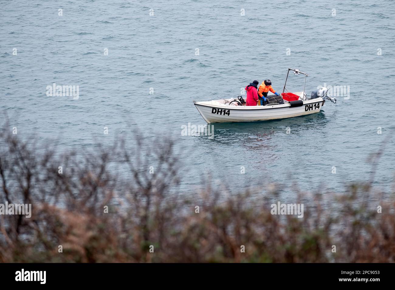Zwei Fischer in einem kleinen Boot an Bord eines Hummertopfs oder einer Hummerfalle aus dem Meer, nachdem er am frühen Tag am Ort zurückgelassen worden war Stockfoto