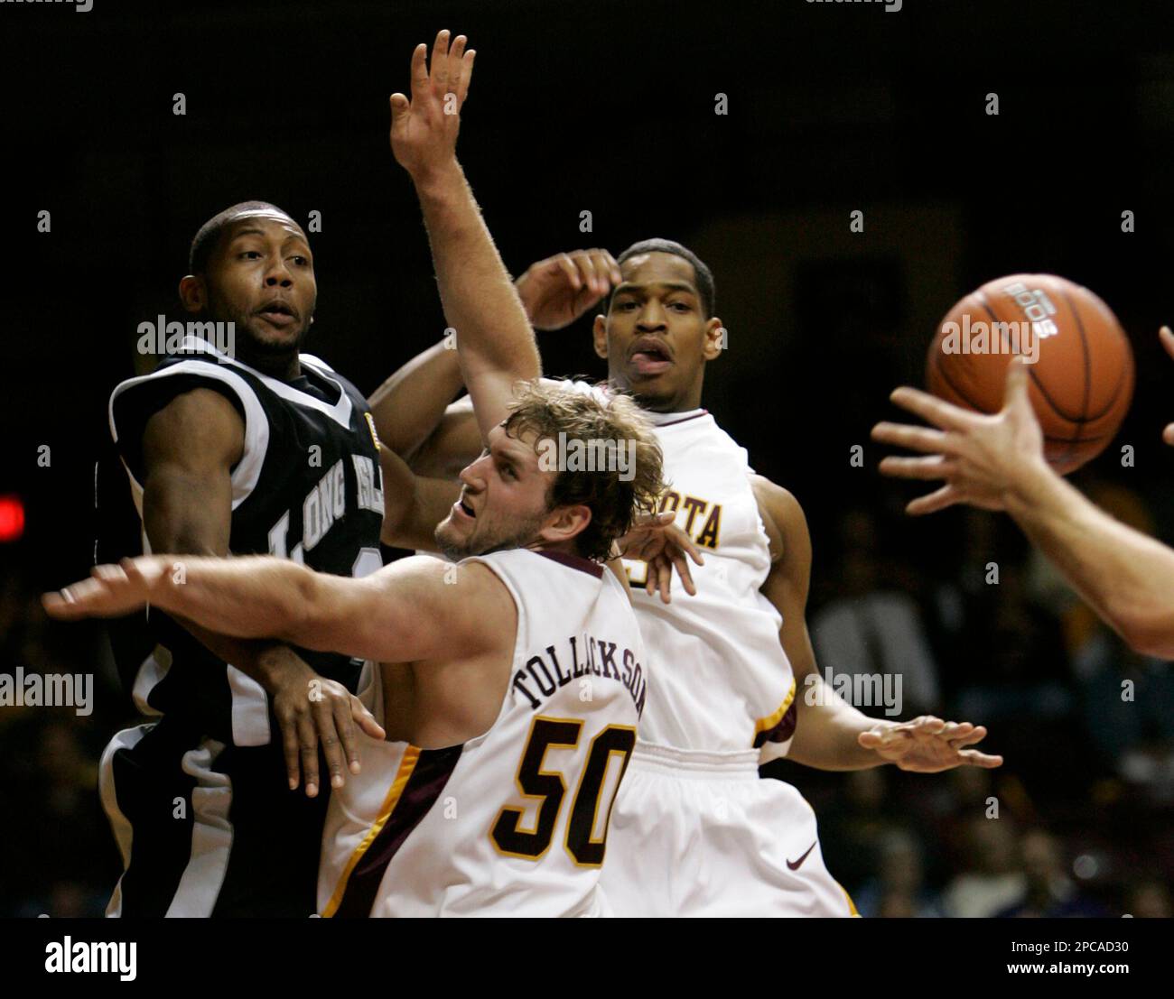 Long Island guard Aubin Scott, left, passes the ball to a teammate under pressure from Minnesota center Spencer Tollackson (50) and forward Dan Coleman, rear, during the first half of a basketball game in Minneapolis, Friday, Nov. 17, 2006. (AP Photo/Ann Heisenfelt) Stockfoto