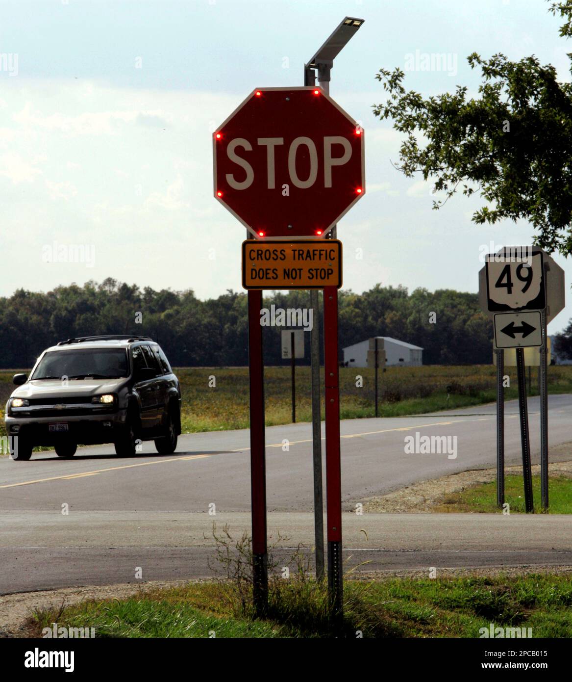 A car stops at a flashing stop sign at the intersections of Ohio 49 and Ohio 707 in rural Mercer County, Ohio, on Sept. 26, 2006. The stop sign has a flashing light in each corner of the sign that allows it to be seen from greater distances, even in daylight. The intersection had been the scene of numerous accidents. To improve traffic safety without busting their budgets, states are installing the cable barriers, painting distance dots on roads to discourage tailgating and placing stop signs that light up like Christmas trees at dangerous intersections. (AP Photo/Al Behrman) Stockfoto