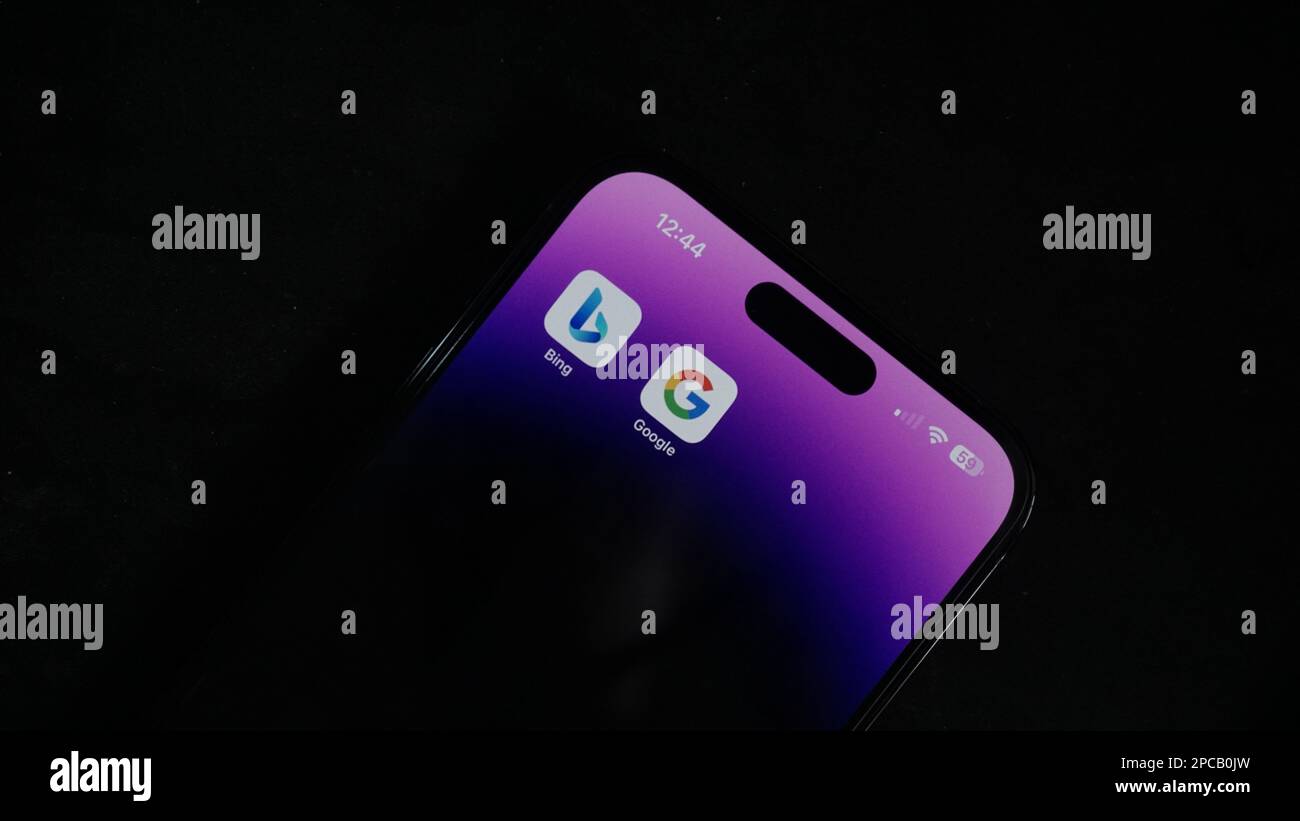 AI-Krieg, Bing gegen Google. Google gegen Microsoft, Bard gegen ChatGPT. IPhone 14 pro max. Im dunklen Hintergrund. Stockfoto