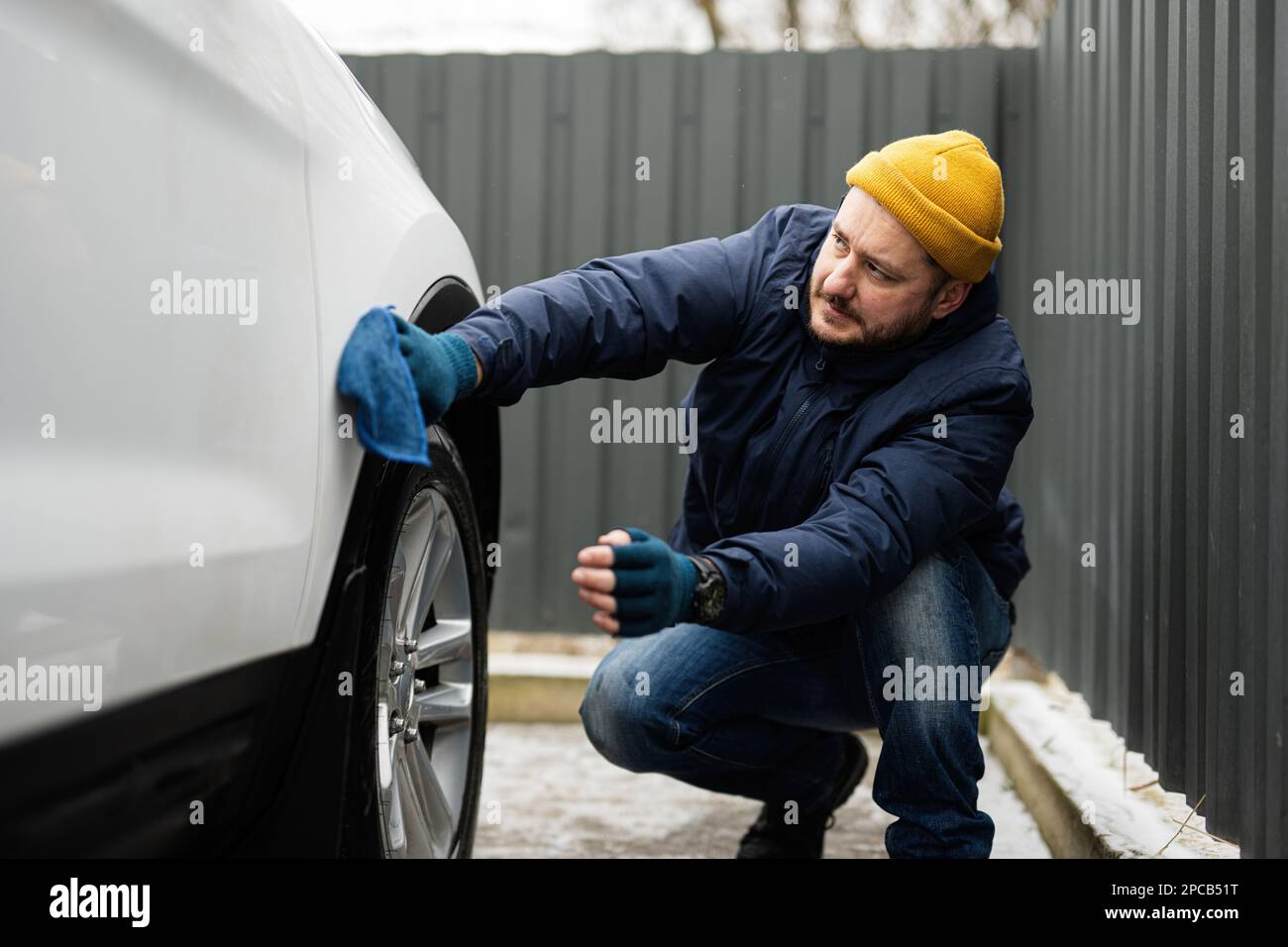 Der mann wischt die amerikanische suv-autohaube nach dem waschen