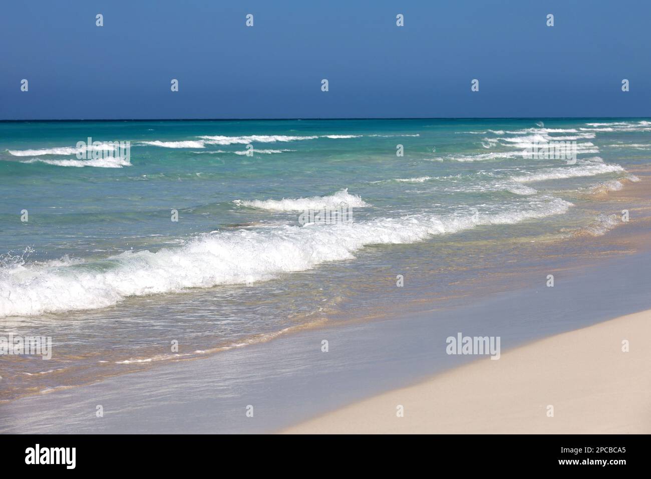 Meeresstrand mit weißem Sand, Blick auf azurblaue Wellen und klaren Himmel. Hintergrund für Urlaub in paradiesischer Natur Stockfoto