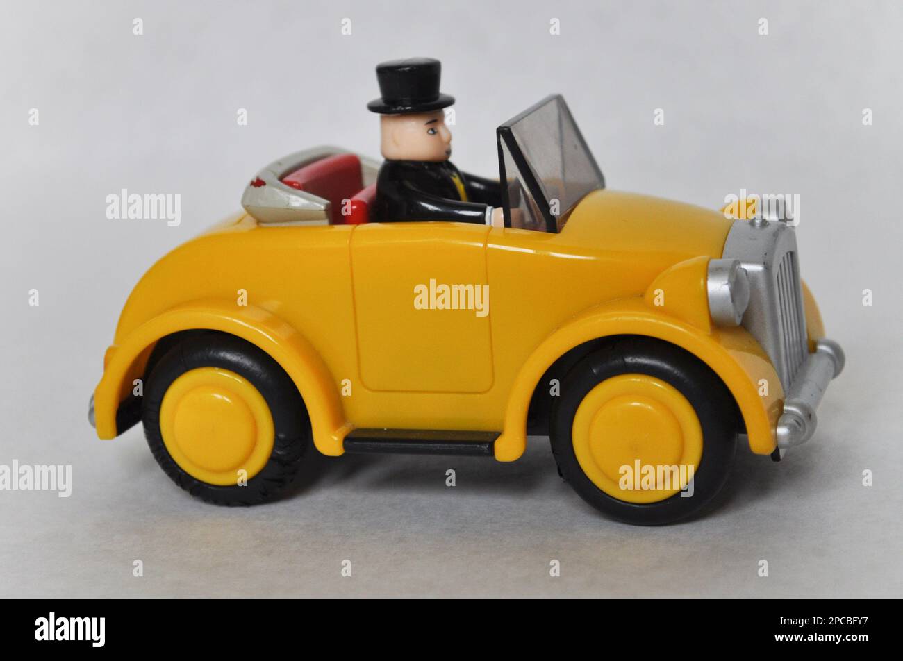 Sir Topham Hatt (der fette Controller) fährt ein gelbes Plastikauto aus der Thomas the Tank Engine Serie Stockfoto