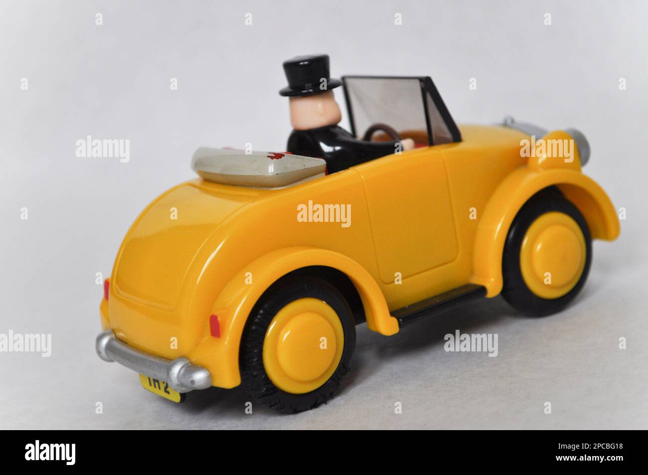 Sir Topham Hatt (der fette Controller) fährt ein gelbes Plastikauto aus der Thomas the Tank Engine Serie Stockfoto