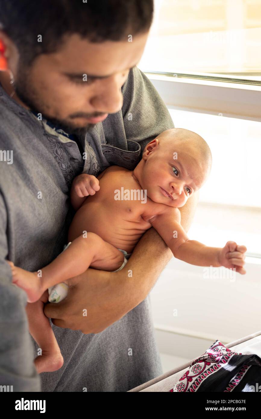 Neugeborene ohne Kleidung, von ihrem Vater gehalten, um Sonnenlicht ausgesetzt zu werden, um ihren Gelbsucht zu senken Stockfoto