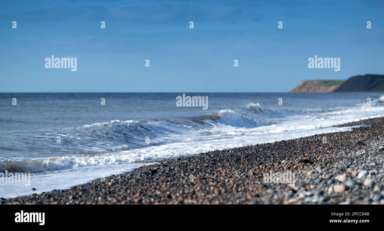 Wellen schlagen auf einen steinigen Strand vor Bootle in Cumbria an der Küste der Irischen See. Cumbria, Großbritannien. Stockfoto