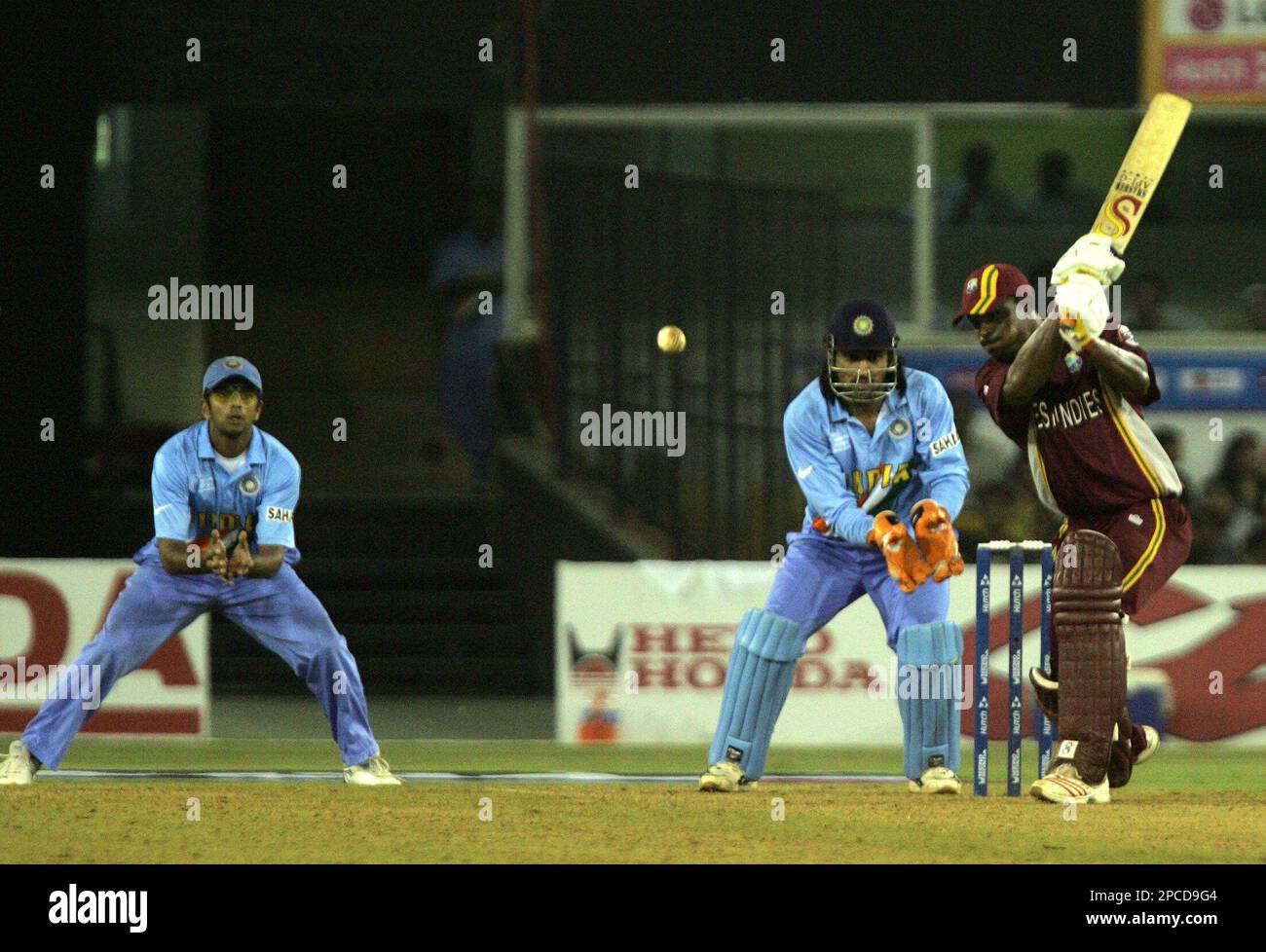 West Indian cricketer Runako Morton strikes a ball as India's captain Rahul Dravid, left, and Mahendra Singh Dhoni, centre, look on during the ICC Champions Trophy cricket tournament match in Ahmadabad, India, Thursday Oct. 26, 2006. West Indies won the match by 3 wickets. (AP Photo/Saurabh Das) Stockfoto