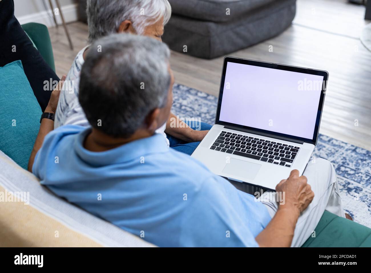 Ein birassisches Seniorenpaar, das den Laptop benutzt, während es sich auf dem Sofa im Wohnzimmer entspannt, Kopierbereich. Unverfälscht, Liebe, zusammen, Ruhestand, Bildschirm, Zuhause, Technologie Stockfoto
