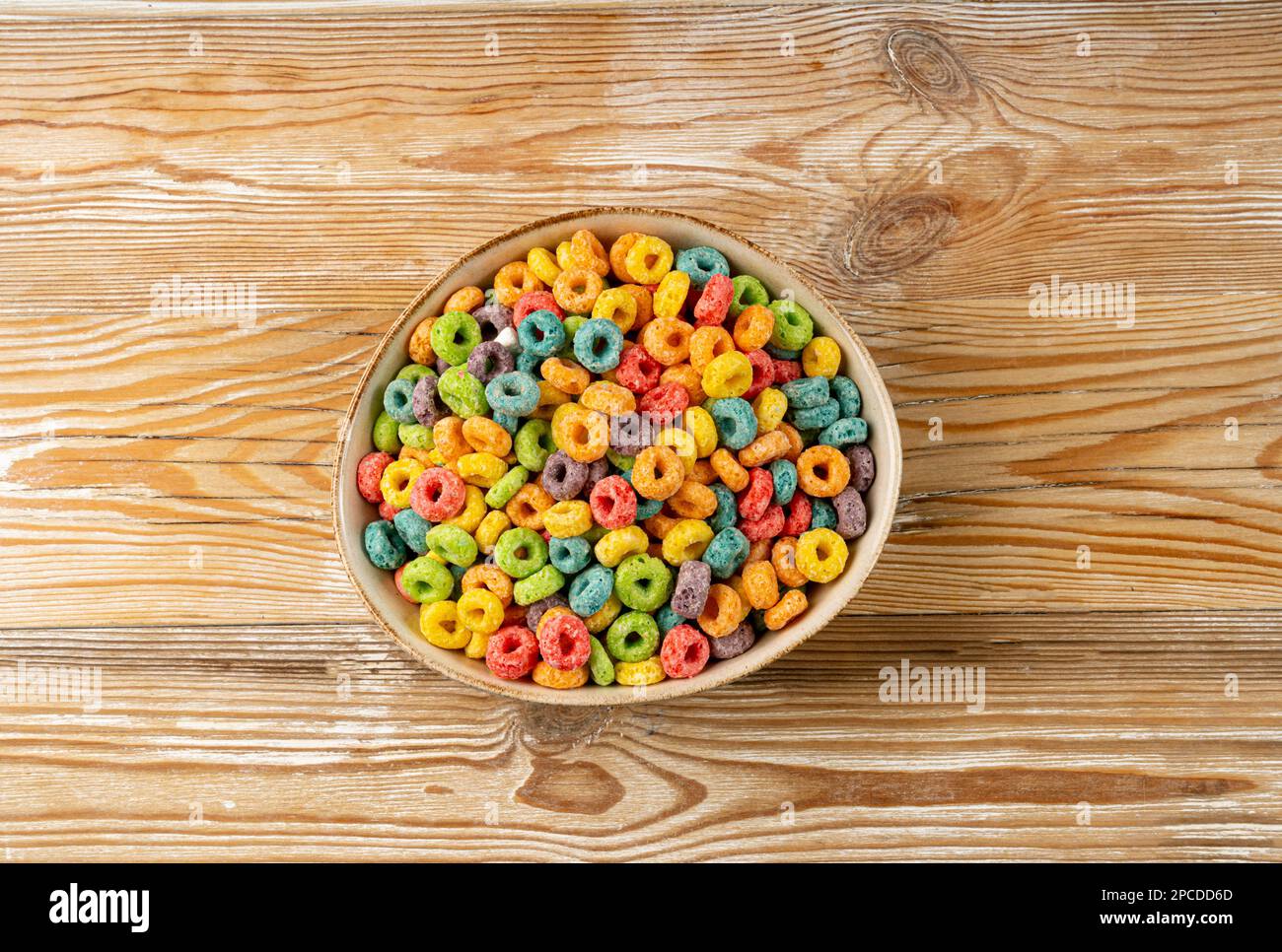 Farbenfrohe Frühstücksringe, Fruit Loops, fruchtige Cerealien-Ringe, farbenfrohe Corn Cerealien auf Holzhintergrund Stockfoto