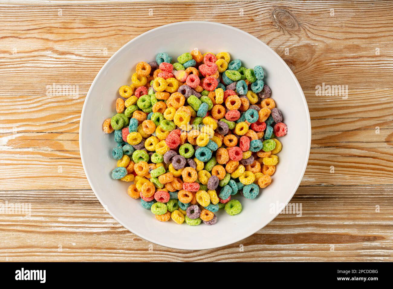 Farbenfrohe Frühstücksringe, Fruit Loops, fruchtige Cerealien-Ringe, farbenfrohe Corn Cerealien auf Holzhintergrund Stockfoto