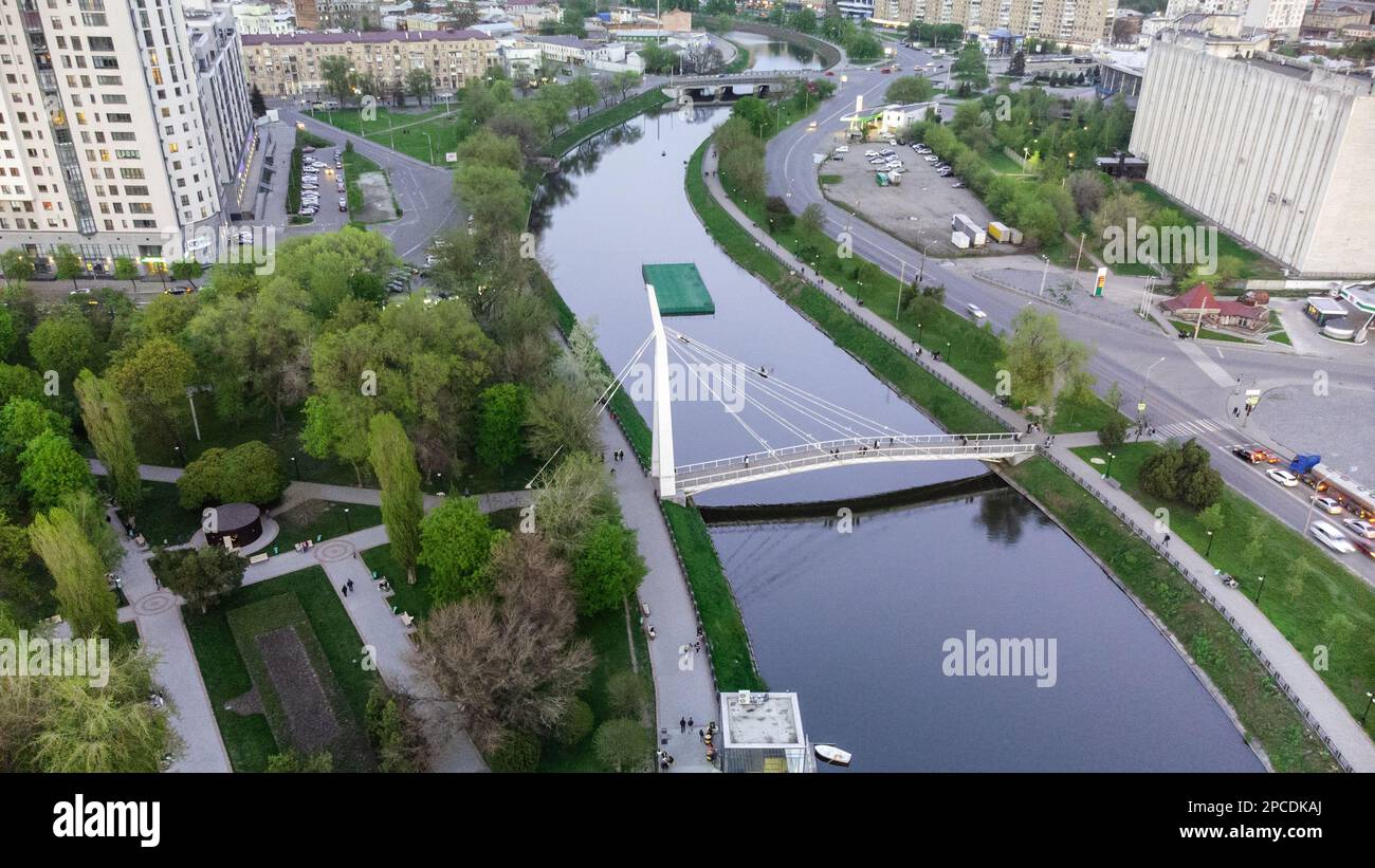 Fußgängerbrücke über den Fluss Kharkiv (Mist Zakokhanykh) Blick nach unten, beliebter Ort für Paare. Frühlingsblick aus der Vogelperspektive auf grauen Charkiv, Reise Stockfoto