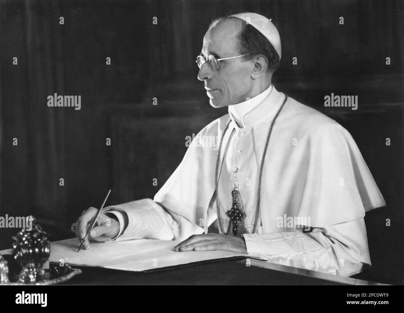 1950 Ca, ITALIEN : der Papst PIO XII ( Eugenio Maria Giuseppe Giovanni Pacelli , 1876 - 1958 ), Foto von Baumgartner , St. Gallen - RELIGIONE CATTOLICA - KATHOLISCHE RELIGION - Rituto - Porträt - PAPA - Schreibtisch - Scrittoio - scrivania - Occhiali - Linse - Città del VATICANO - VATIKANSTADT - profilo - Profil - Pennino - Linse - Occhiali da vista ---- Archivio GBB Stockfoto