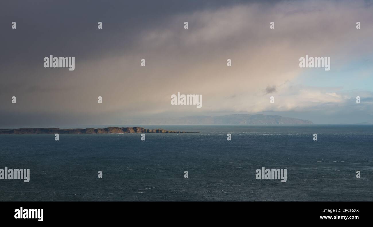 Das Sonnenlicht beleuchtet die weite Meereslandschaft von Rathlin Island durch einen Ausbruch von Sturmwolken vor der Antrim Coast in Nordirland Stockfoto