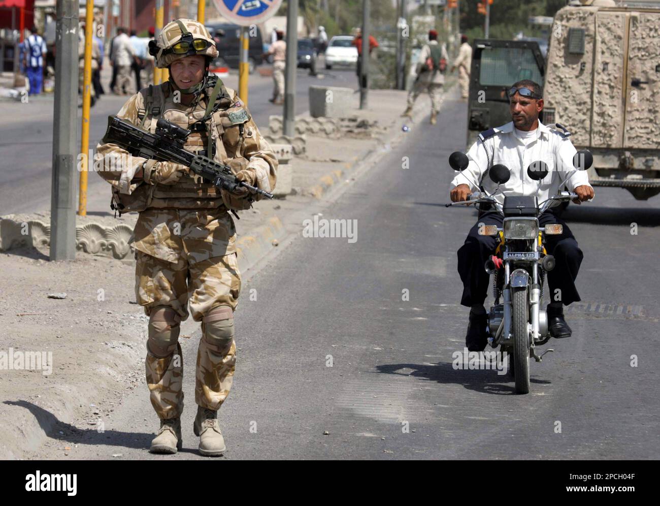 A British soldier stands guard as an Iraqi traffic policeman rides past, at the site of a roadside bomb explosion, in Basra, 550 kilometers (340 miles) southeast of Baghdad, Iraq, Saturday Sept. 23, 2006. A roadside bomb Saturday targeting a British soldiers convoy, missed and injured two civilians, police said. (AP Photo/Nabil Al-Jurani) Stockfoto