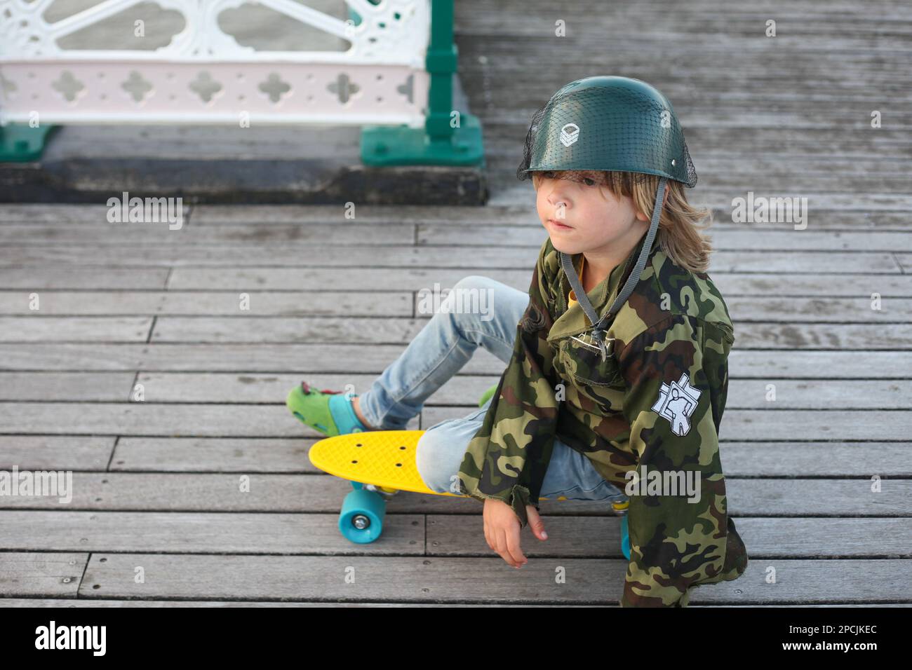 Ein Junge sitzt auf einem gelben Skateboard Stockfoto