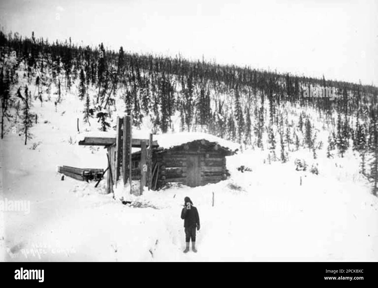 Mann, der im Schnee vor der Hütte auf Sulphur Creek, Yukon Territory, 1898 steht Stockfoto