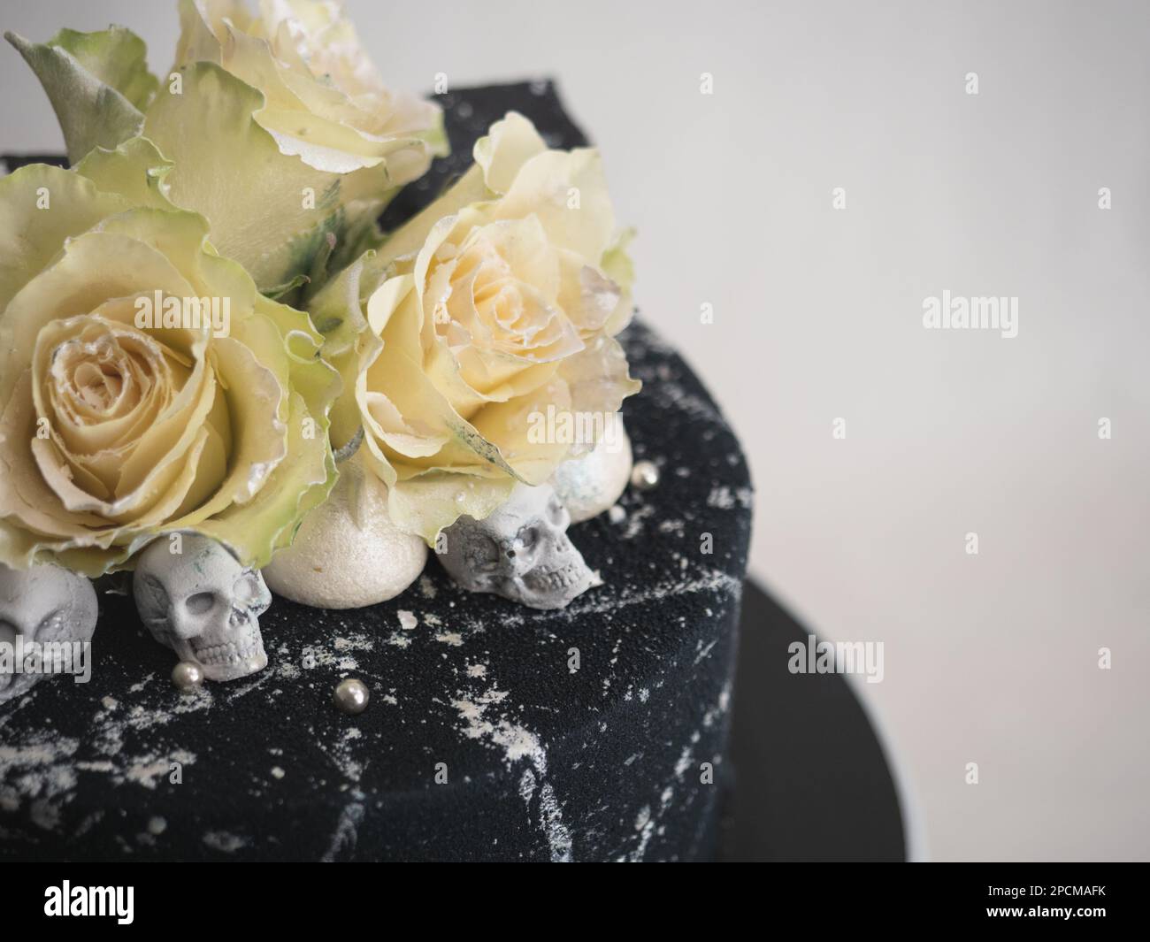 Geburtstagskuchen mit schwarzem Airbrush-Maler, Milchkuchen, zwei silberne Rosen, versprühte und essbare Schokoladenköpfe und silberne Pinselstriche Stockfoto