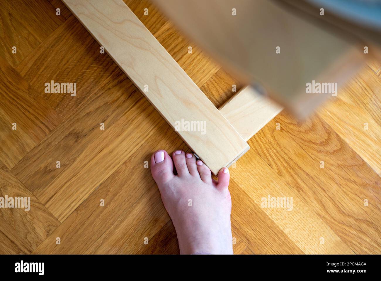 Frau schlug mit dem kleinen Zeh auf die Möbel. Zwischenfall zu Hause. Verletzung des kleinen Fingers des Fußes Stockfoto
