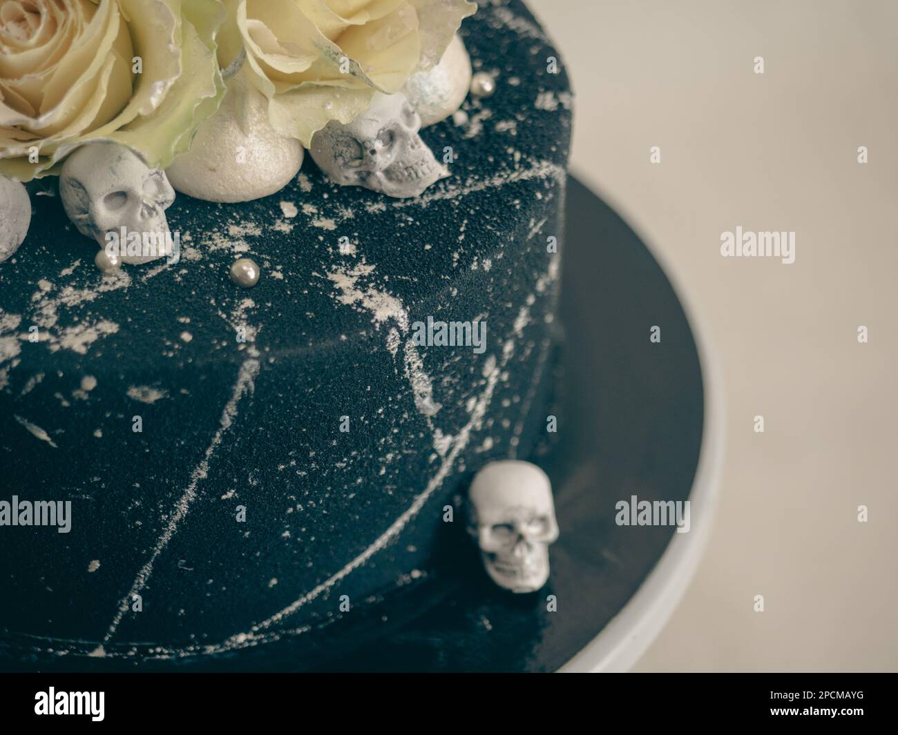 Geburtstagskuchen mit schwarzem Airbrush-Maler, Milchkuchen, zwei silberne Rosen, versprühte und essbare Schokoladenköpfe und silberne Pinselstriche Stockfoto