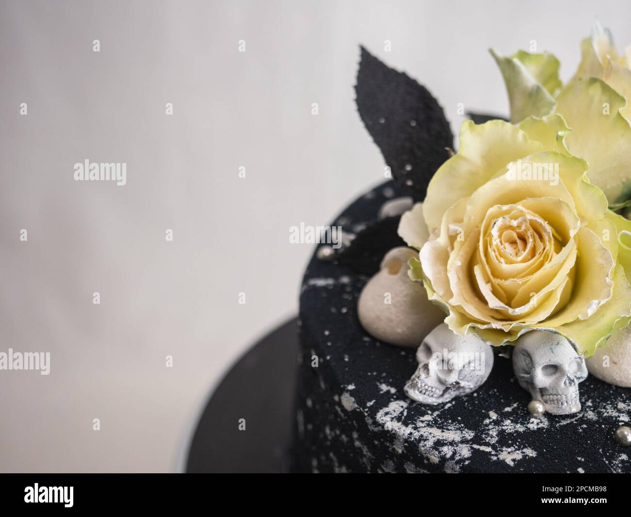 Geburtstagskuchen mit schwarzem Airbrush-Maler, Milchkuchen, zwei silberne Rosen, versprühte und essbare Schokoladenköpfe und silberne Pinselstriche Stockfoto