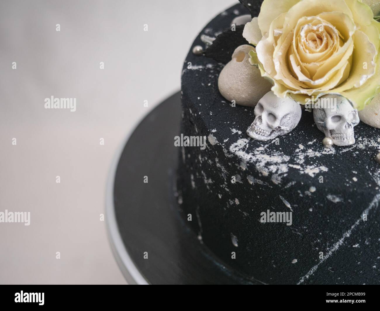 Geburtstagskuchen mit schwarzem Airbrush-Maler, Milchkuchen, zwei silberne Rosen, versprühte und essbare Schokoladenköpfe und silberne Pinselstriche Stockfoto