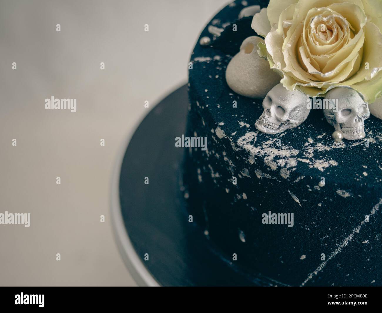 Geburtstagskuchen mit schwarzem Airbrush-Maler, Milchkuchen, zwei silberne Rosen, versprühte und essbare Schokoladenköpfe und silberne Pinselstriche Stockfoto