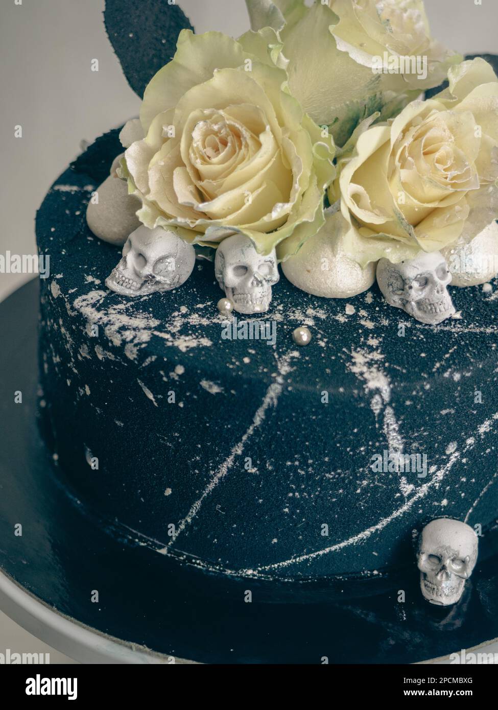 Geburtstagskuchen mit schwarzem Airbrush-Maler, Milchkuchen, zwei silberne Rosen, versprühte und essbare Schokoladenköpfe und silberne Pinselstriche Stockfoto