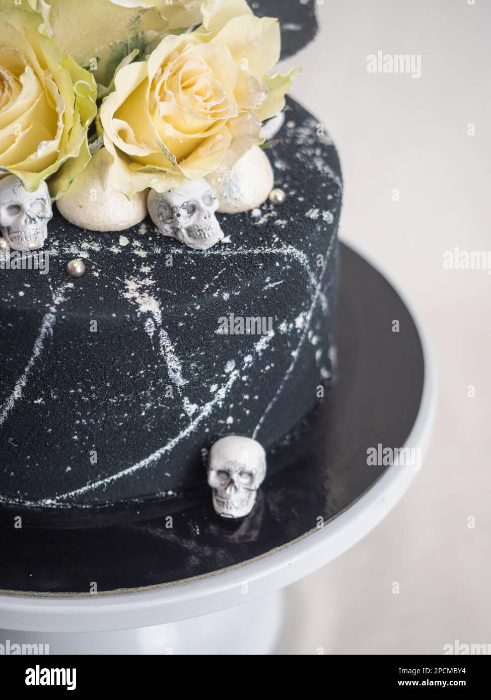 Geburtstagskuchen mit schwarzem Airbrush-Maler, Milchkuchen, zwei silberne Rosen, versprühte und essbare Schokoladenköpfe und silberne Pinselstriche Stockfoto