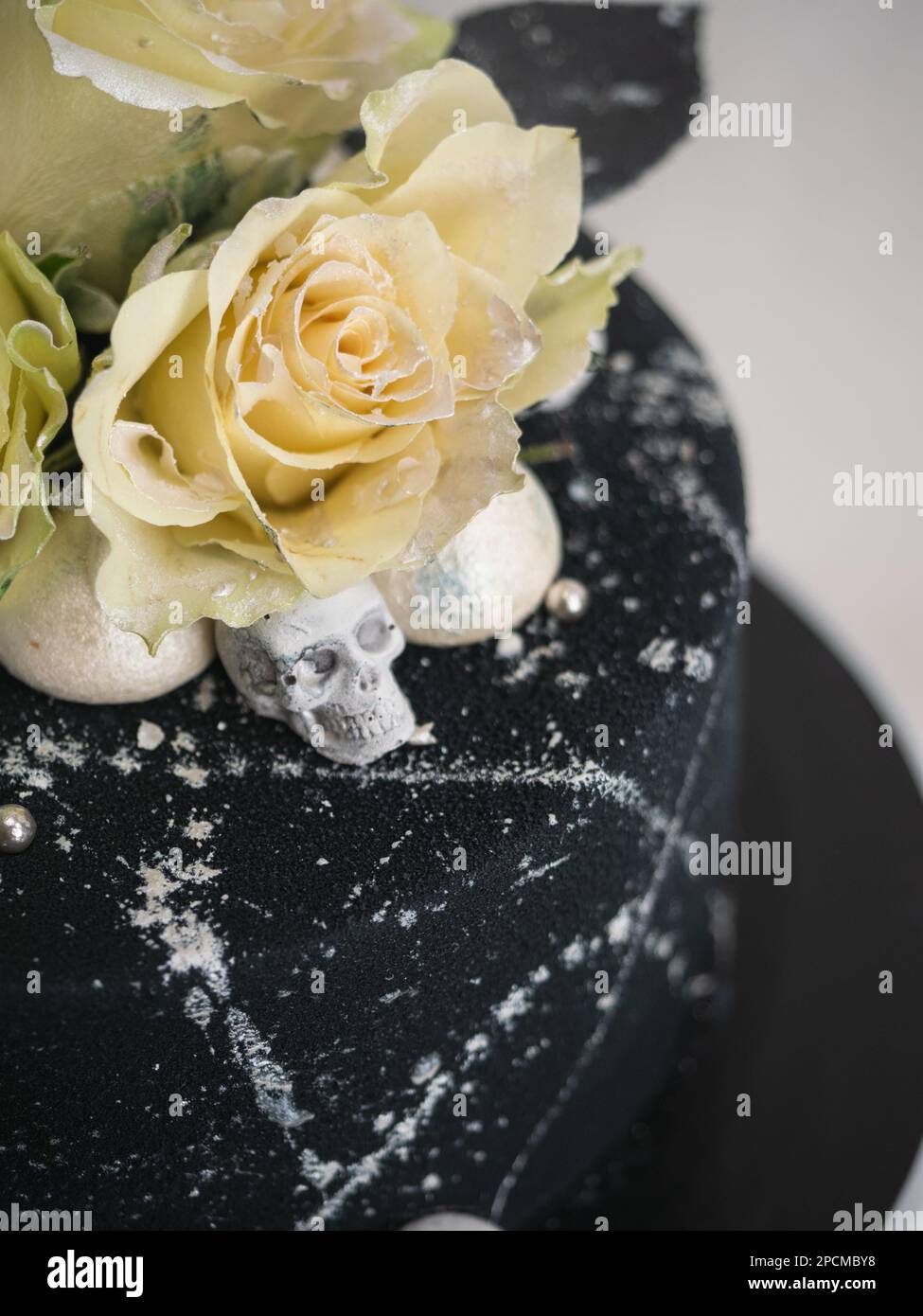 Geburtstagskuchen mit schwarzem Airbrush-Maler, Milchkuchen, zwei silberne Rosen, versprühte und essbare Schokoladenköpfe und silberne Pinselstriche Stockfoto