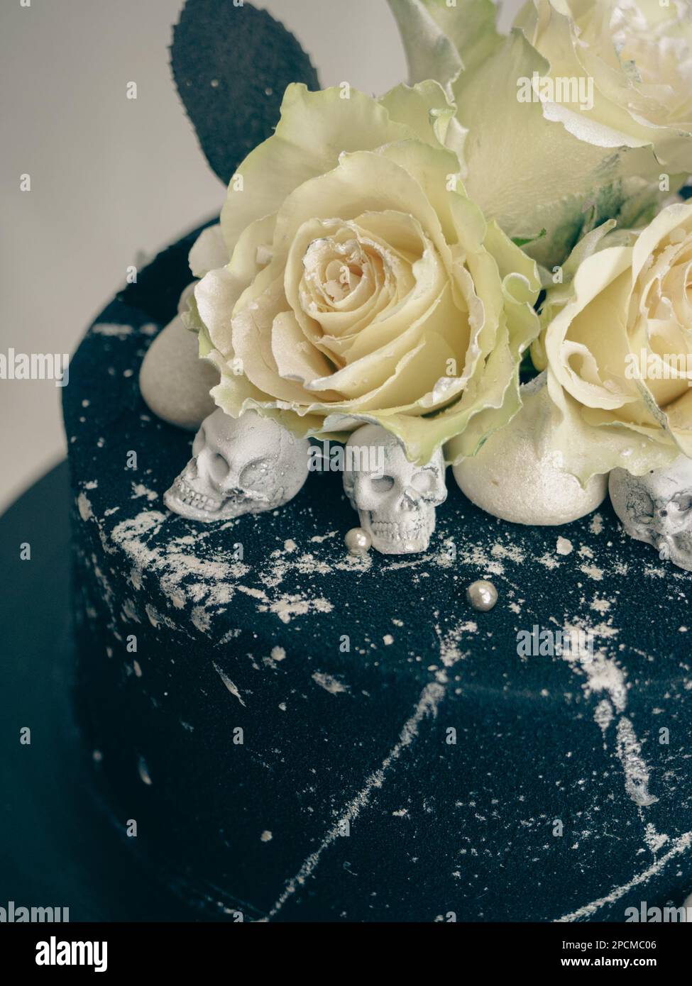 Geburtstagskuchen mit schwarzem Airbrush-Maler, Milchkuchen, zwei silberne Rosen, versprühte und essbare Schokoladenköpfe und silberne Pinselstriche Stockfoto