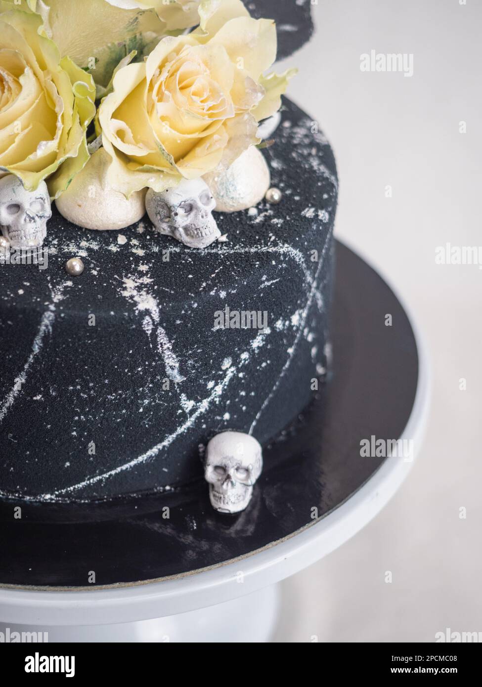 Geburtstagskuchen mit schwarzem Airbrush-Maler, Milchkuchen, zwei silberne Rosen, versprühte und essbare Schokoladenköpfe und silberne Pinselstriche Stockfoto