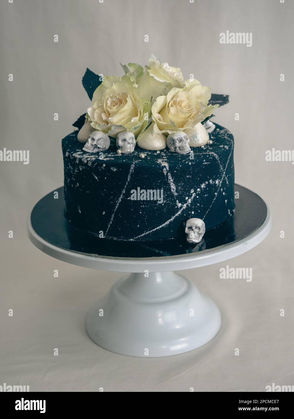Geburtstagskuchen mit schwarzem Airbrush-Maler, Milchkuchen, zwei silberne Rosen, versprühte und essbare Schokoladenköpfe und silberne Pinselstriche Stockfoto