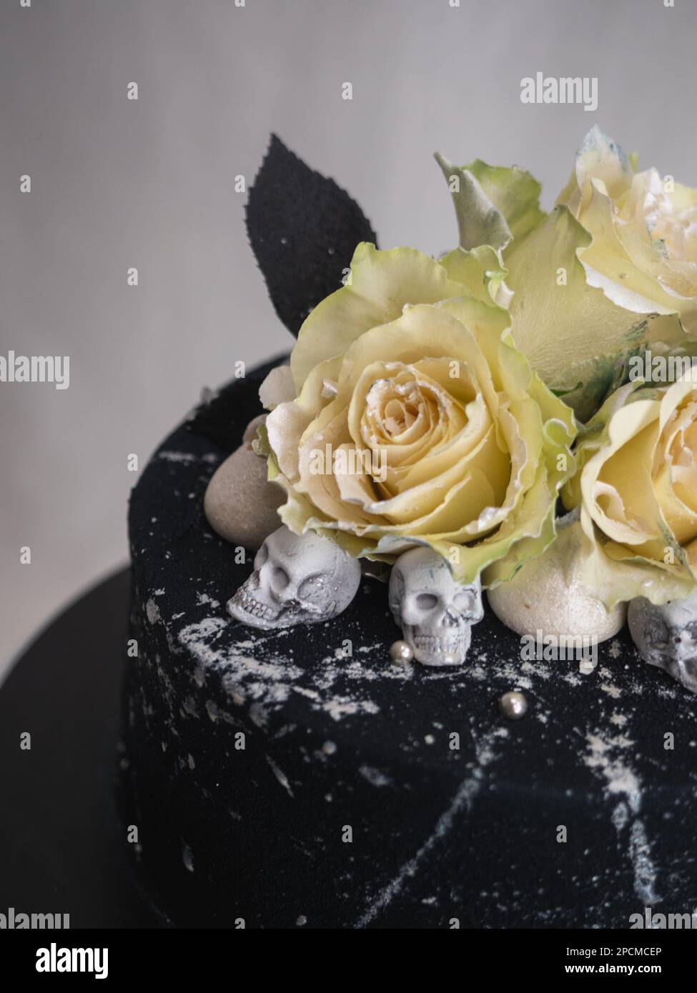 Geburtstagskuchen mit schwarzem Airbrush-Maler, Milchkuchen, zwei silberne Rosen, versprühte und essbare Schokoladenköpfe und silberne Pinselstriche Stockfoto