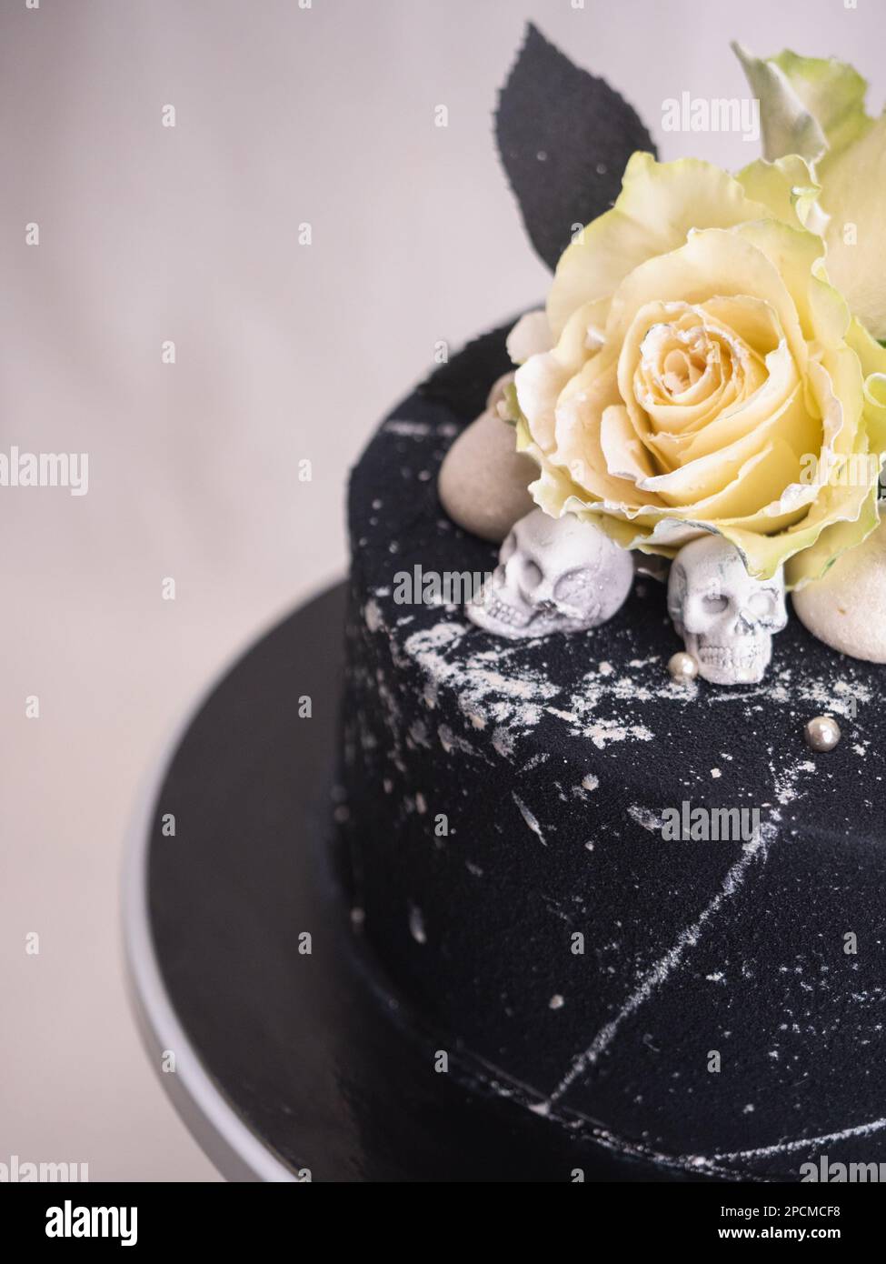 Geburtstagskuchen mit schwarzem Airbrush-Maler, Milchkuchen, zwei silberne Rosen, versprühte und essbare Schokoladenköpfe und silberne Pinselstriche Stockfoto