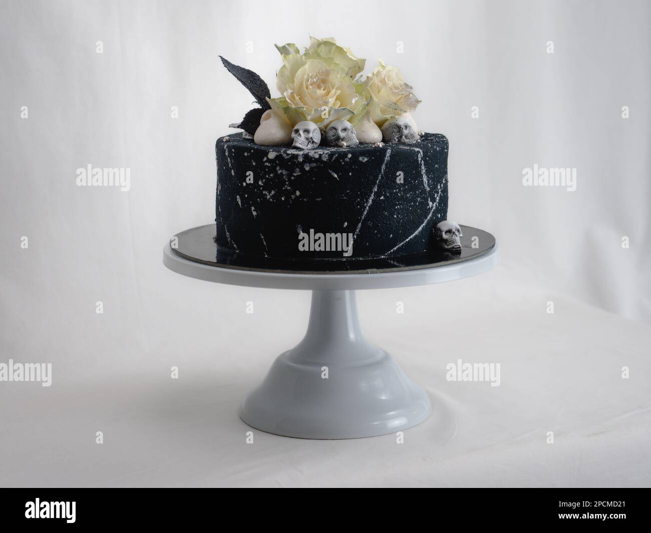 Geburtstagskuchen mit schwarzem Airbrush-Maler, Milchkuchen, zwei silberne Rosen, versprühte und essbare Schokoladenköpfe und silberne Pinselstriche Stockfoto