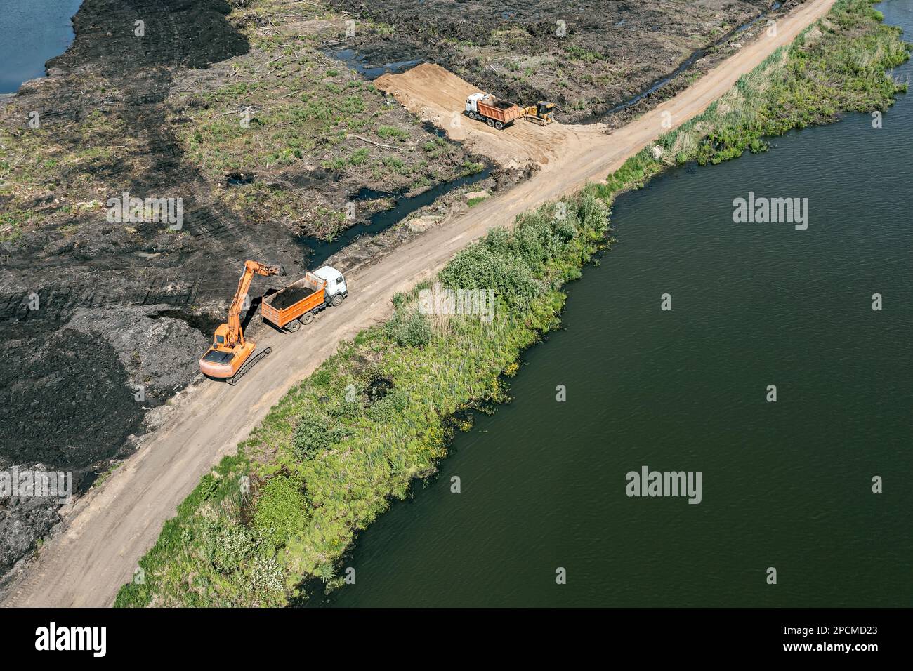 Baumaschinen auf der Baustelle. Der Bagger lädt Erde in einen Lkw. Luftaufnahme von der fliegenden Drohne. Stockfoto