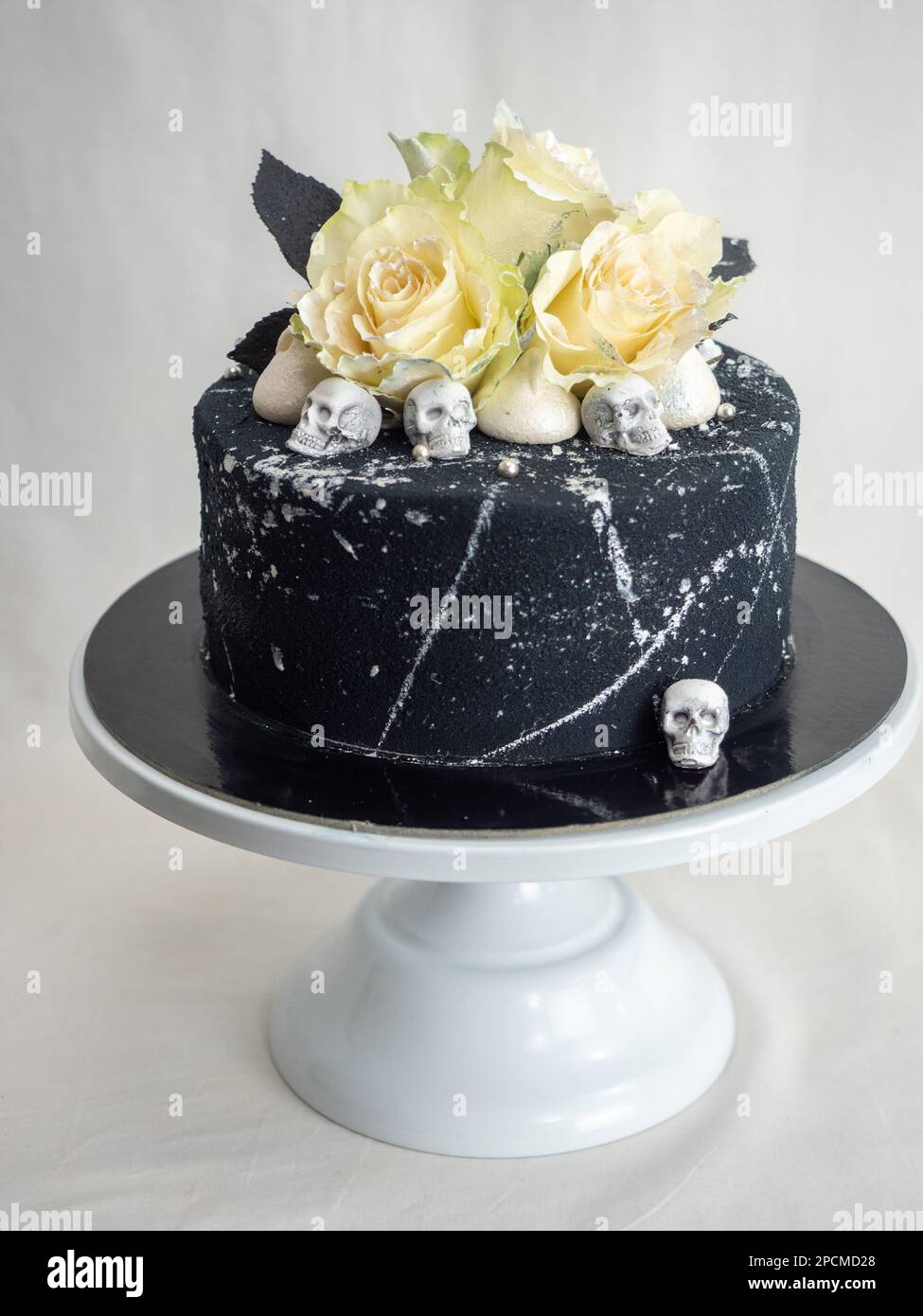 Geburtstagskuchen mit schwarzem Airbrush-Maler, Milchkuchen, zwei silberne Rosen, versprühte und essbare Schokoladenköpfe und silberne Pinselstriche Stockfoto