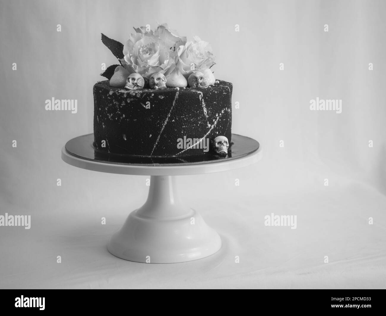 Geburtstagskuchen mit schwarzem Airbrush-Maler, Milchkuchen, zwei silberne Rosen, versprühte und essbare Schokoladenköpfe und silberne Pinselstriche Stockfoto