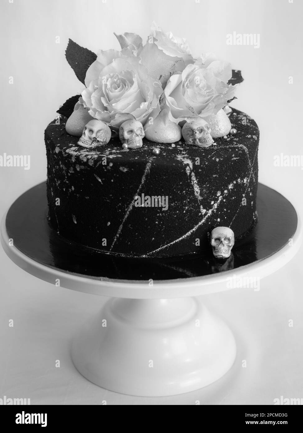 Geburtstagskuchen mit schwarzem Airbrush-Maler, Milchkuchen, zwei silberne Rosen, versprühte und essbare Schokoladenköpfe und silberne Pinselstriche Stockfoto