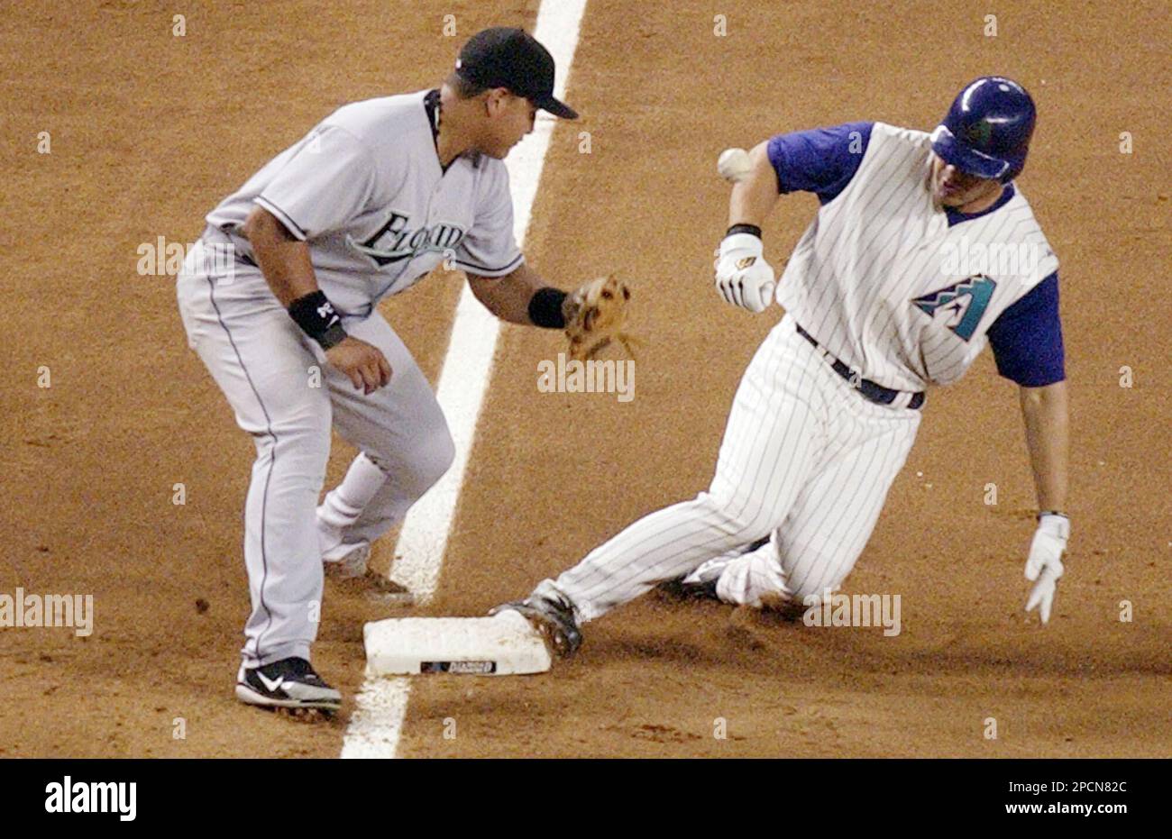 Arizona Diamondbacks' Carlos Quentin, right, slides safely into third base with a three-run triple in the fourth inning as Marlins third baseman Miguel Cabrera bobbles the throw during their baseball game Saturday, Aug. 12, 2006, in Phoenix. Quentin's triple, part of a six-run inning, scored teammates Conor Jackson, Luis Gonzalez and Orlando Hudson. (AP Photo/Tom Hood) Stockfoto