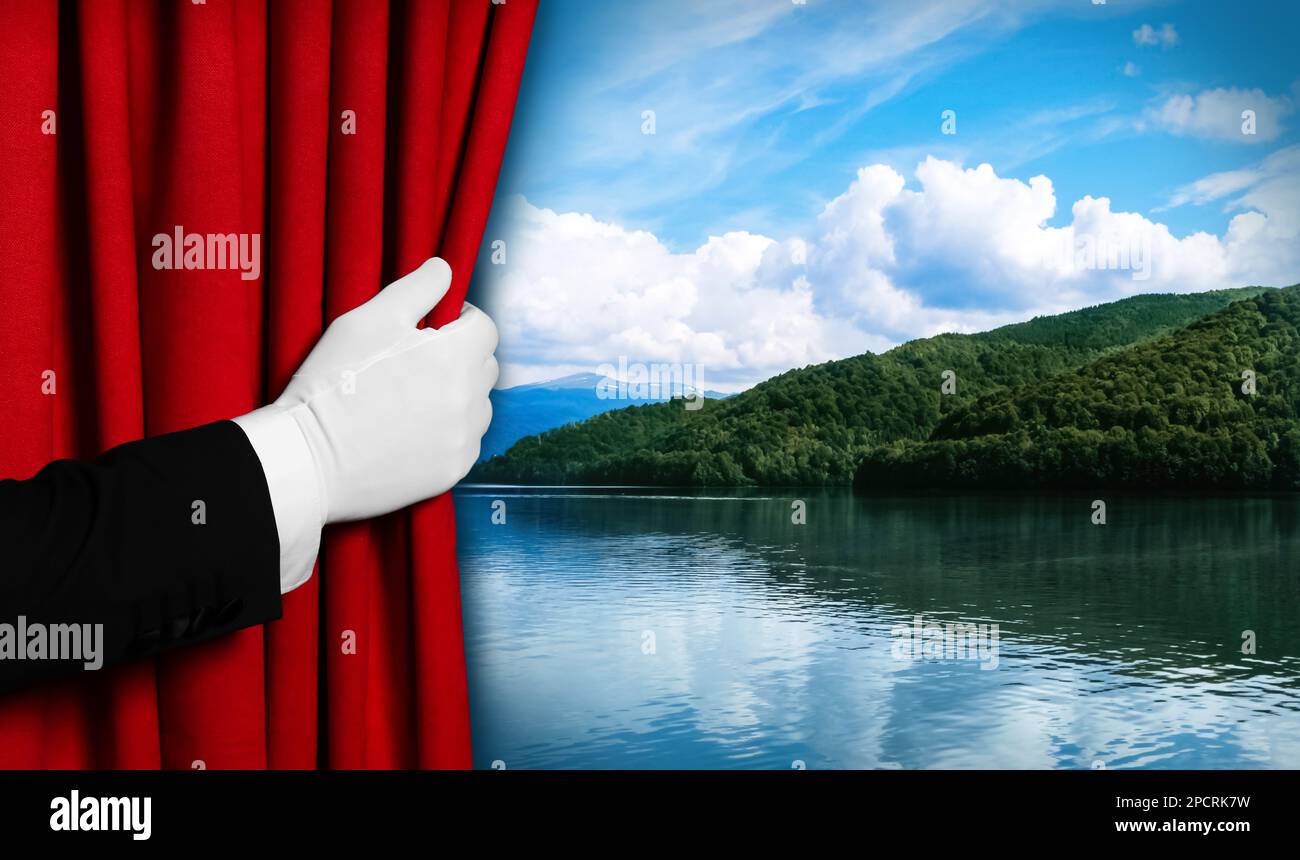 Ein Mann öffnet den roten Vorhang und bietet einen malerischen Blick auf den Fluss und die Berge im Hintergrund Stockfoto