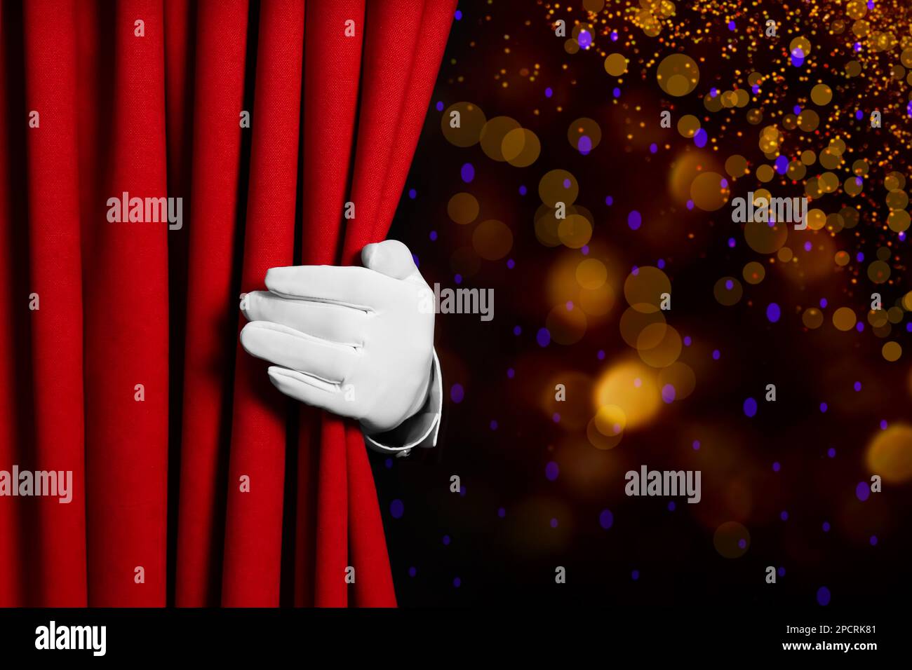 Mann öffnet roten Vorhang vor unscharfen Lichtern. Bokeh-Effekt Stockfoto