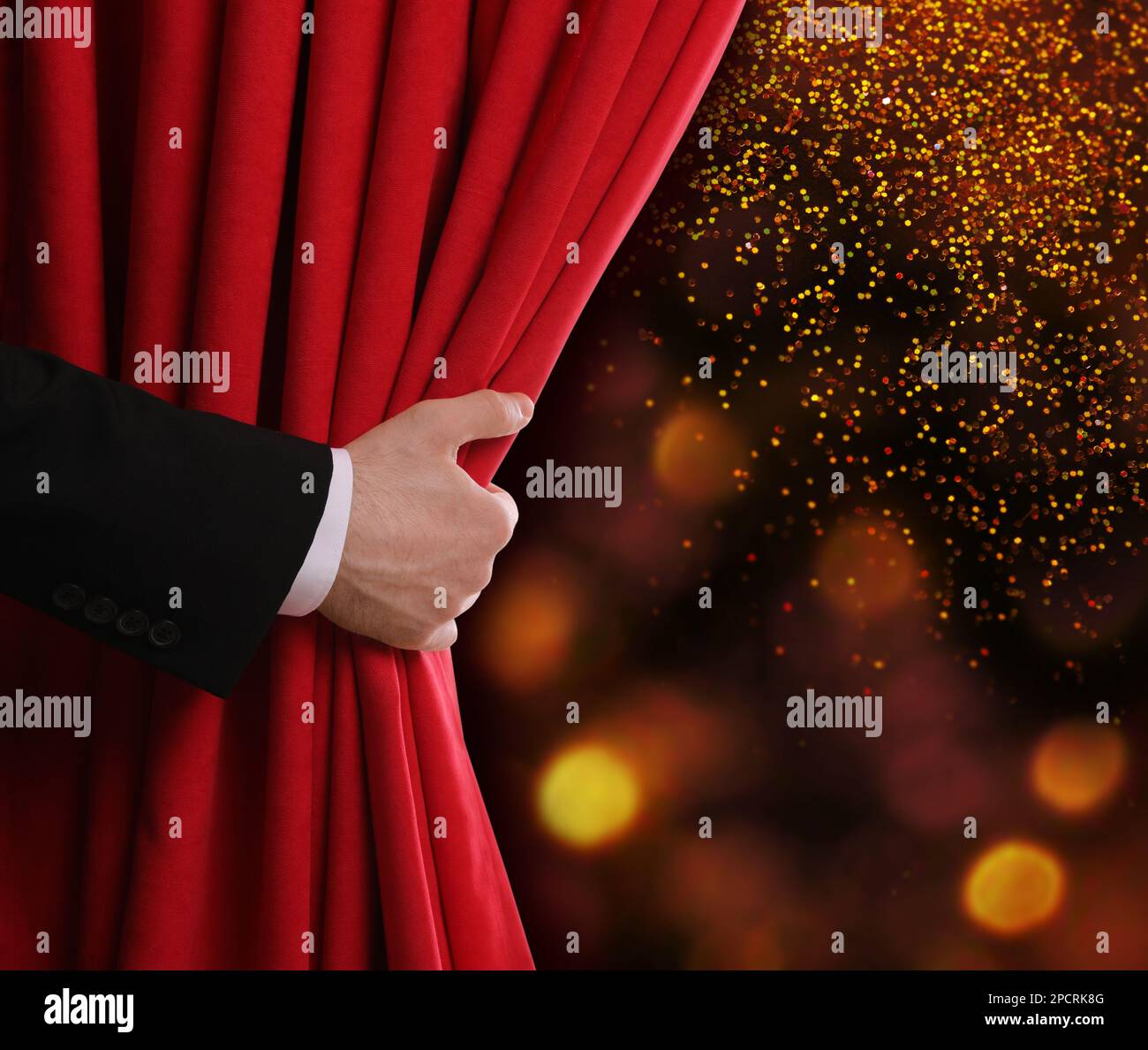 Mann öffnet roten Vorhang vor unscharfen Lichtern. Bokeh-Effekt Stockfoto