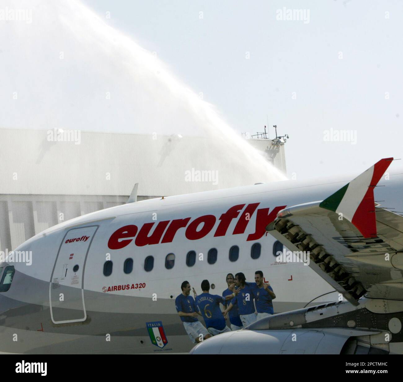 Airport firefighters spray a friendly water fontaine to the airplane with the Italian national soccer team on board, at the airport in Duesseldorf, western 'Germany, Monday July 10, 2006, when the world cup winning team flies home to Italy. The plane is painted with a scene of jubilating soccer players. (AP Photo/Hermann J. Knippertz) Stockfoto