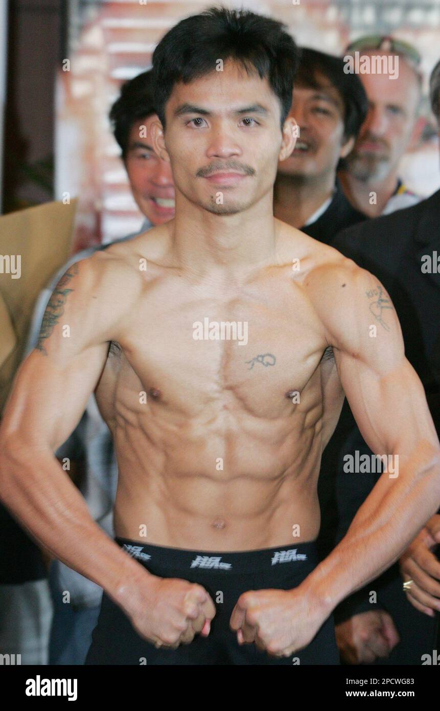 Philippine boxing champion Manny Pacquiao flexes his muscles during official weigh-in at suburban Mandaluyong city, east of Manila, Philippines Saturday, July 1, 2006, the eve of his scheduled 12-round WBC super featherweight title bout against Mexican challenger Oscar Larios dubbed "Mano-A-Mano." Pacquiao, guaranteed a US$1 million, tipped in at 129.5 lbs while Larios, who gets US$450,000, weighed 129 lbs. (AP Photo/Bullit Marquez) Stockfoto