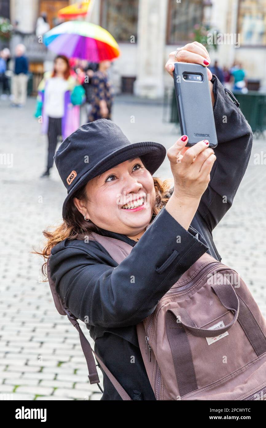 Lady on the Grand Place in Brüssel, erleben Sie große Freude beim Fotografieren des Turms des Rathauses. Stockfoto