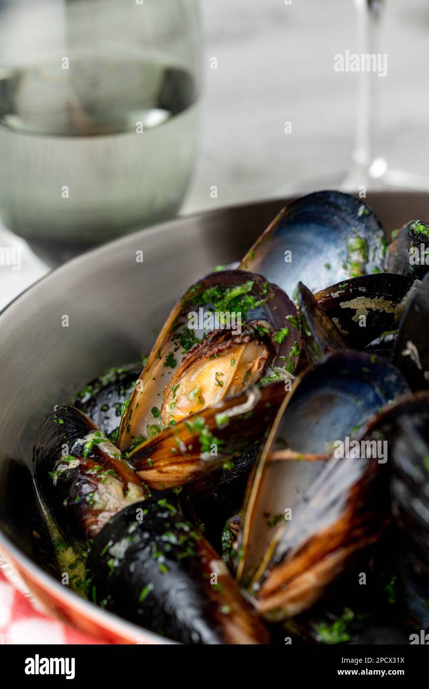 Gebackene blaue Muscheln in scharfer Schale mit Zitrone in einem schwarzen gusseisernen Topf Stockfoto