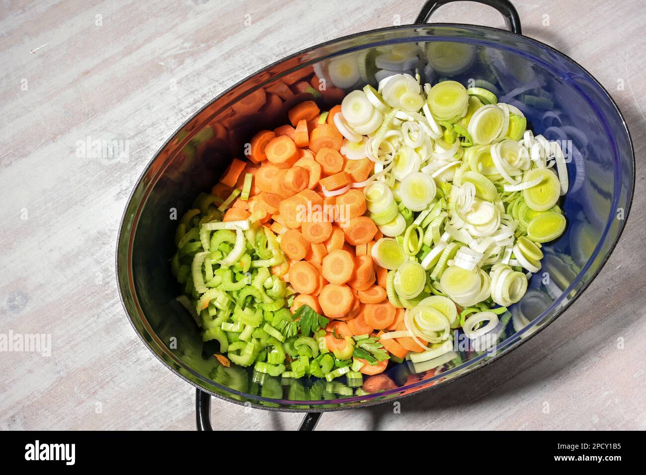 Gehacktes rohes Gemüse wie Karotten, Sellerie und Lauch in einem Braten für eine geschmorte Suppe oder ein Eintopfgericht, Kochkonzept für zu Hause, Blick von oben Stockfoto