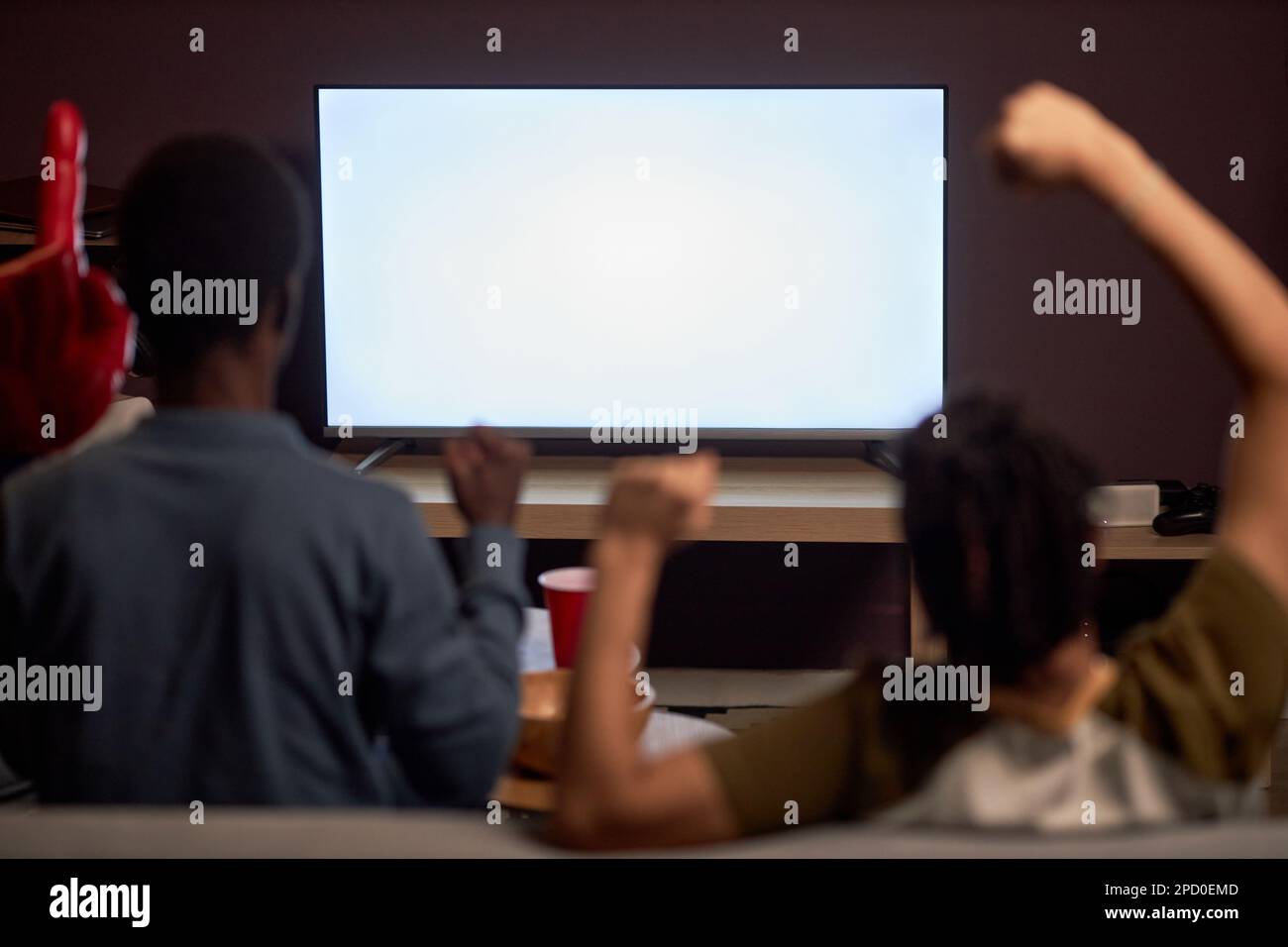 Rückblick auf zwei begeisterte Sportfans, die sich das Spiel im Fernsehen ansehen, mit einem leeren Bildschirmmodell Stockfoto