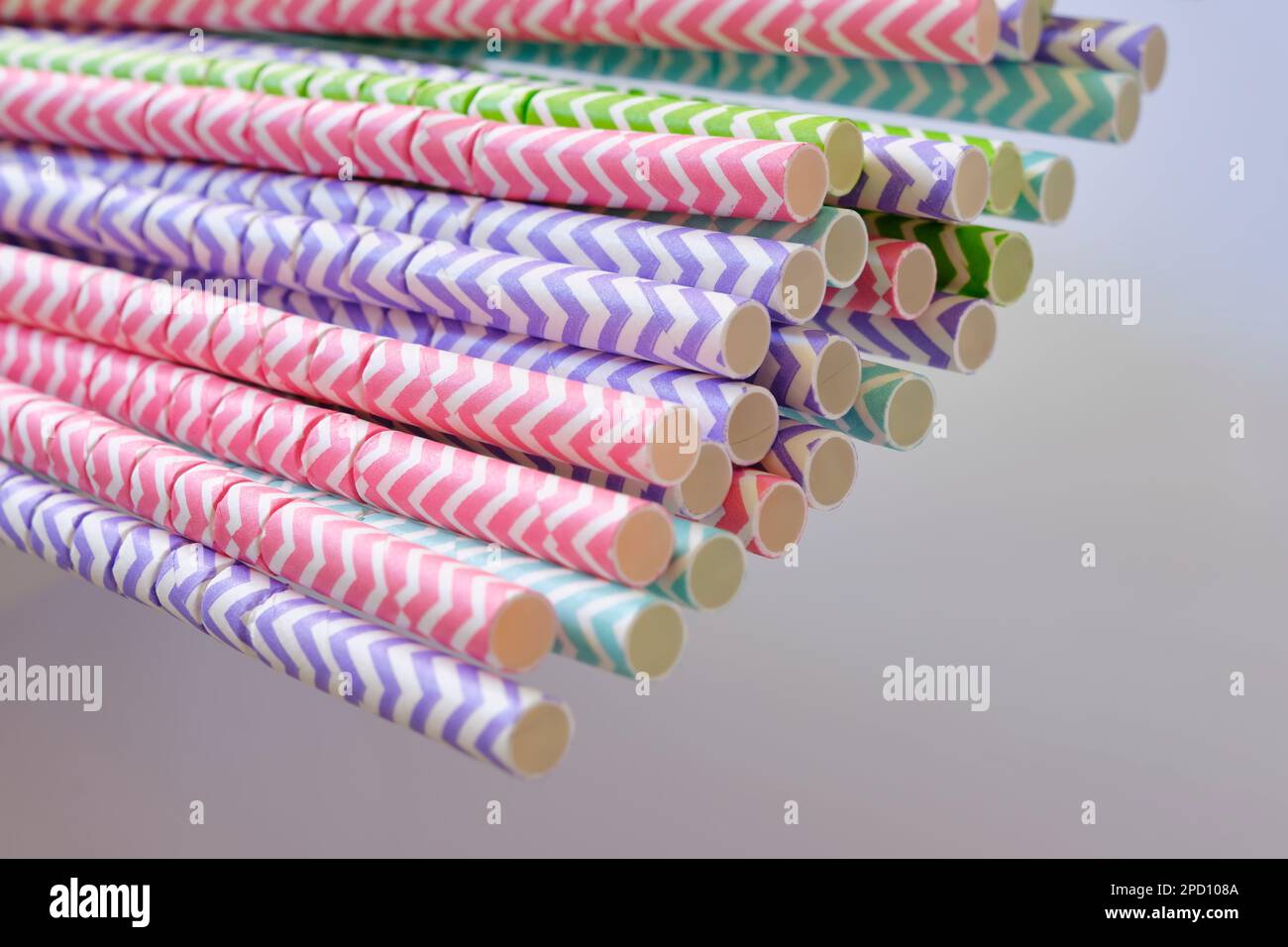 Nahaufnahme von bunten gestreiften Papierhalmen vor einem grauen Hintergrund. Umweltfreundliches Konzept mit selektivem Fokus. Stockfoto